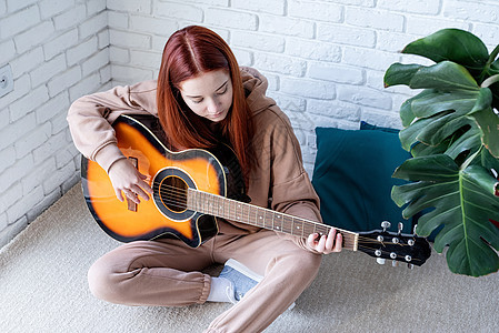在家里弹吉他的年轻女子爱好成人音乐家音乐艺术家吉他手乐趣砖墙幸福女孩图片