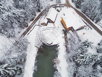 雪落在风景秀丽的偏远地区 那里有冰冻的湖泊和冬季森林中间的小屋图片