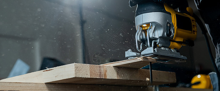 一名男子在车间用电锯砍木板的缝合装置上工具木匠木材工作职场机器作坊木制品男性工作台图片