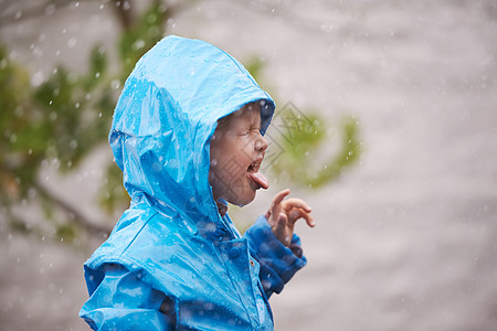 一个可爱的小女孩在雨中在外面玩耍 外面放着风呢?图片