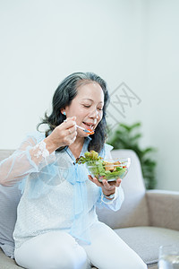 一位年长的亚洲妇女通过吃沙拉来照顾自己的健康桌子蔬菜成人烹饪家庭老年食品厨房退休水果图片