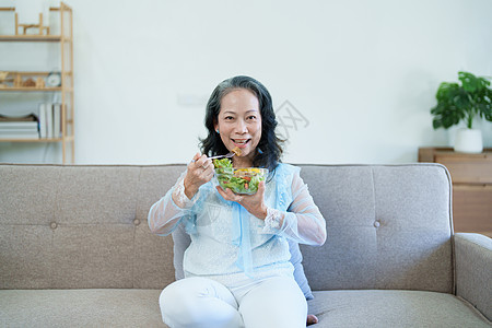 一位年长的亚洲妇女通过吃沙拉来照顾自己的健康午餐夫妻老年成人烹饪家庭桌子蔬菜女性食品图片
