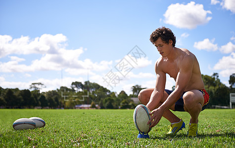 一个年轻的橄榄球运动员 准备在运动场上踢一脚的比赛图片
