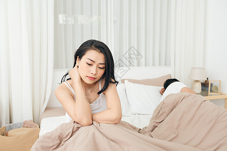 我们有个问题 年轻不高兴的女孩坐在床的边缘 对着她的男朋友 躺在床上呢女朋友卧室女性离婚丈夫夫妻妻子家庭压力情绪化图片