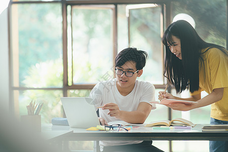 一个亚裔学生正在阅读书本和学习 一起教书中学友谊学费导师智力知识图书愿望电脑校园图片