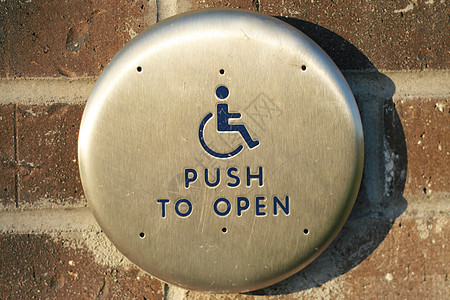 残疾人在外部砖墙上按下打开按钮图片