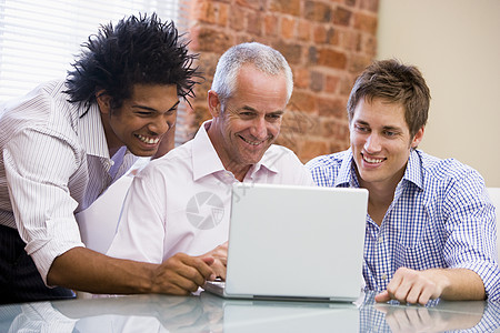 三名坐在办公室的商务人士微笑着笔记本电脑图片