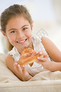 年轻女孩在客厅里笑着吃披萨片家庭餐厅食品一个女孩孩子们微笑饮食孩子享受食物图片