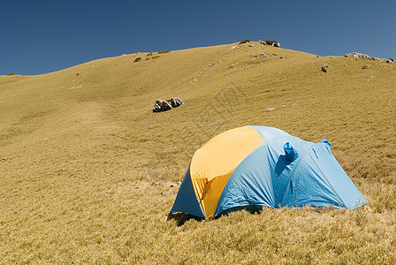 在高山草原上设置特别帐篷蓝色木头游客公园爬坡阳光顶峰登山运动环境图片