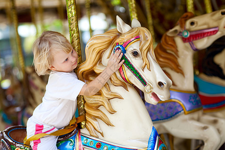 骑马的儿童闲暇幸福女孩马戏团童年产蛋马匹公园拥抱旋转图片