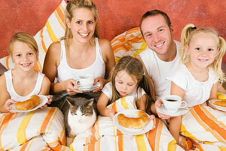 小孩和猫家人和猫咪在床上吃早餐乐趣微笑羊角爸爸妈妈睡眠父亲房间夫妻唤醒背景