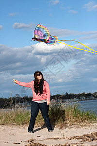 女孩飞行Kite在海滩上风筝航班蝴蝶享受娱乐天空海岸线乐趣细绳空气图片