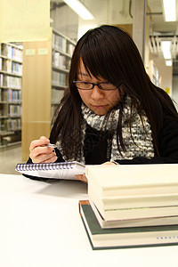 亚裔女性在大学深造女士收藏书架女孩教育微笑课堂工作书柜学生图片