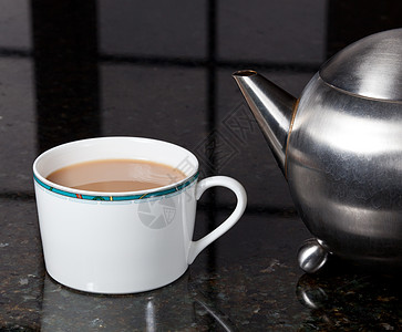 不锈钢杯子来自不锈钢铁茶壶的茶早餐厨房台面溪流窗户液体茶杯反射酿造宏观背景