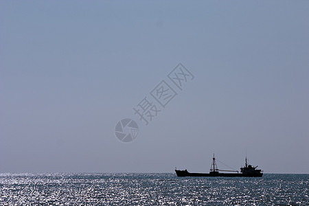 海洋和天空蓝色波浪的地平线背景上的货轮图片