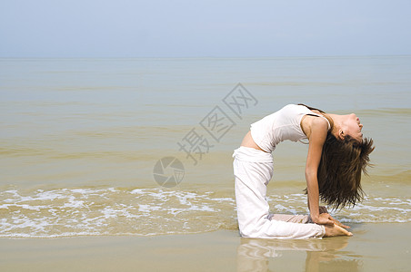 在海滩上做瑜伽的亚洲女孩女性运动海洋日出专注体操天空日落女士岩石图片
