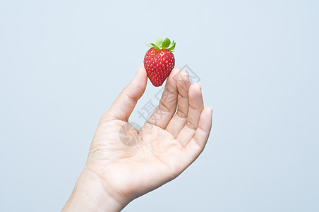 一只手握着一根草莓图片