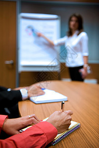 商业研讨会桌边手持笔纸和文件的商家图片
