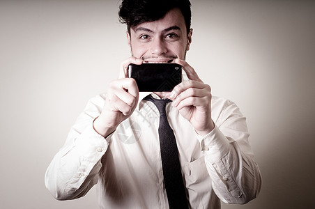 商务人士用电话照相的生意人相片微笑领带成功人士技术手机美男子照片商业图片