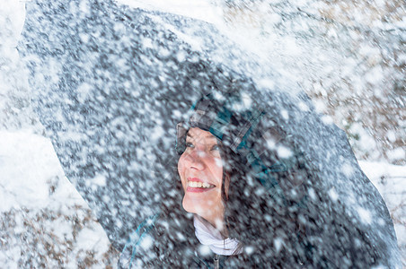 雪中带着雨伞的女孩雪花幸福头发微笑女性假期乐趣天气降雪女士背景图片