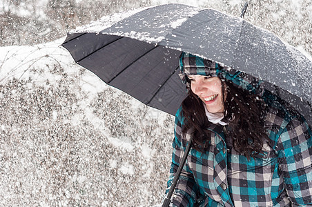 雪中带着雨伞的女孩乐趣幸福头发天气雪花降雪蓝色女士女性薄片背景图片