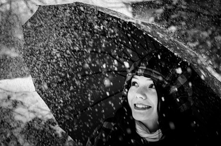 在暴风雪中带着雨伞的年轻女子女性微笑眼睛女士蓝色季节花园雪花青少年天气图片