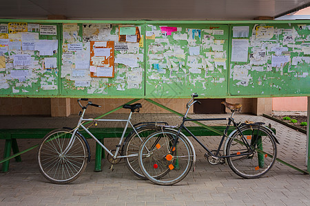 锁海报两辆旧自行车在街上对一个公告板倾斜运输金属踏板控制板旅行民众木板车轮框架海报背景