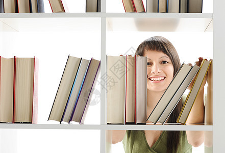 年轻女子在图书馆寻找一本书学生架子教育书架女性学习女士女孩大学学校图片