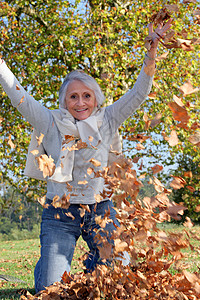 祖母玩着一堆枯叶子的老奶奶背景图片