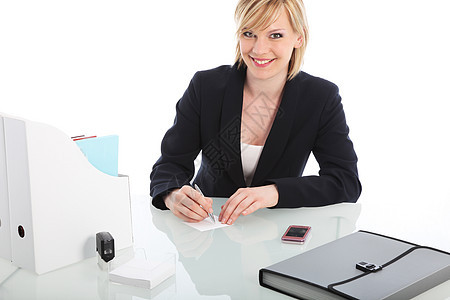 微笑的女商务人士坐在办公桌旁在职的高清图片素材