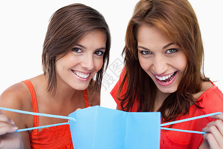 两个少女在笑着时拿着买包的年轻女孩购物女性外表享受长发微笑朋友们乐趣影棚快乐背景图片