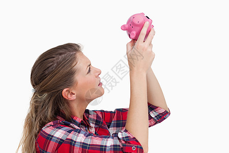 女人在小猪银行里看现金财政经济学粉色银行业破产经济金融白色储蓄图片