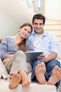 一对年轻夫妇使用平板电脑的肖像互联网房子触摸屏微笑标签享受技术阅读电子邮件冲浪图片
