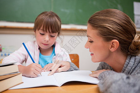 可爱的女学生在老师说话的时候写字图片
