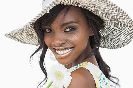 妇女微笑 将白花戴在太阳帽子上图片