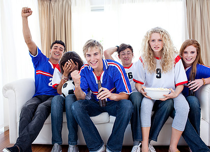 在客厅看足球比赛的少年人手们朋友球衣青春期小吃团体微笑男生食物享受幸福图片