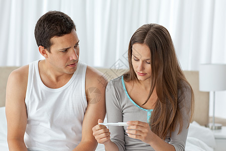 坐在床上看着怀孕测试的夫妻们都担心着呢背景图片