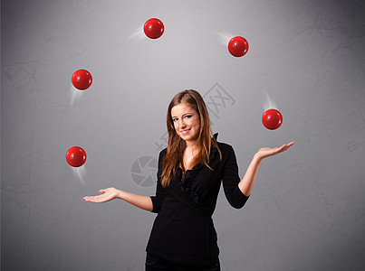 年轻女孩站立和玩弄红色球风险平衡工作乐趣游戏女性戏法者享受专注运动图片