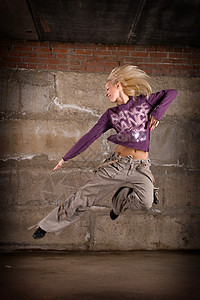 在灰砖墙上跳舞的美丽舞女运动衫培训师演员说唱运动鞋女士姿势霹雳舞女性跳跃图片