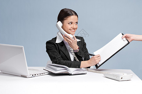 忙碌的女商务人士通过电话交谈电脑写作报告互联网规划师文档笔记本工人微笑缓刑犯图片