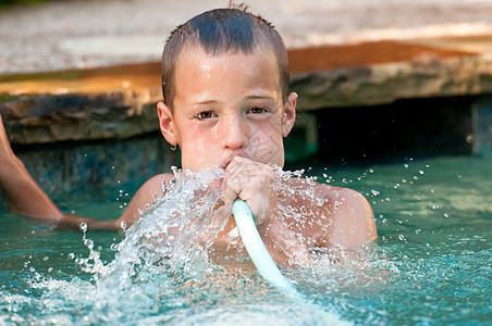 男孩在游泳池里玩水龙头图片