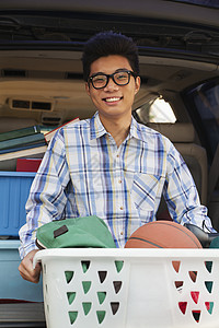 汽车后面有大学宿舍用品的男孩肖像眼镜面包车校园大学生学习学生头发衣篮后备箱棕色图片