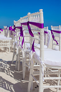 在沙沙滩上装饰有紫色弓的白色婚礼椅子奢华接待海滩幸福宴会派对庆典仪式婚姻服务图片