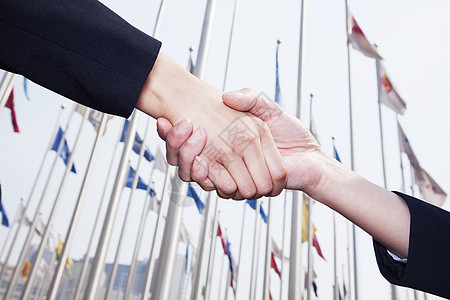 北京两个商业人士握手 背景中挂着旗子 在北京与人握手套装旗帜合伙全球两个人商务协议女性衣冠团队图片