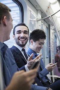 坐在地铁上聊天的三名商务人士坐成一排图片