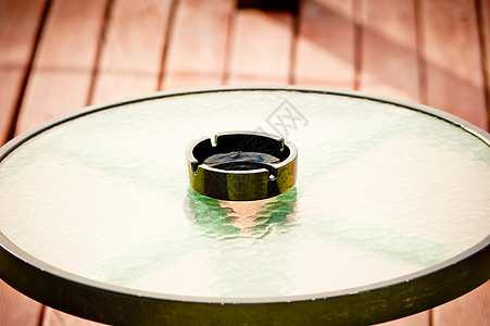 黑色空烟灰缸站在圆形玻璃桌的中间图片