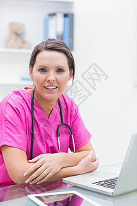 护士电脑在诊所用笔记本电脑微笑护士的肖像背景