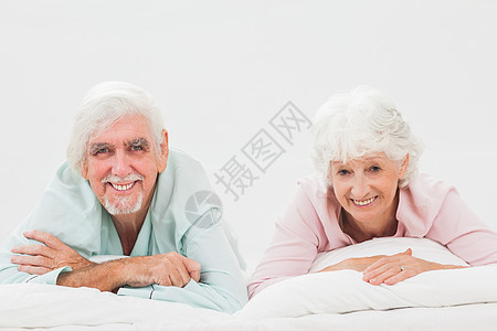 床上快乐的情侣男人男性微笑说谎家庭坐垫羽绒被女士白色头发图片