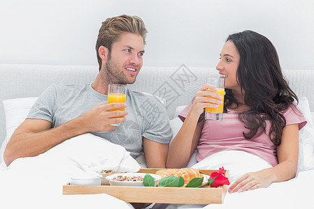 有吸引力的夫妇在床上吃早餐被子夫妻棕色女士伙伴微笑快乐卧室头发橙汁图片