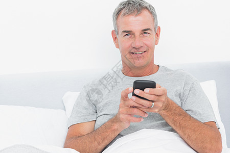 灰色的白发男子在床上发短信图片